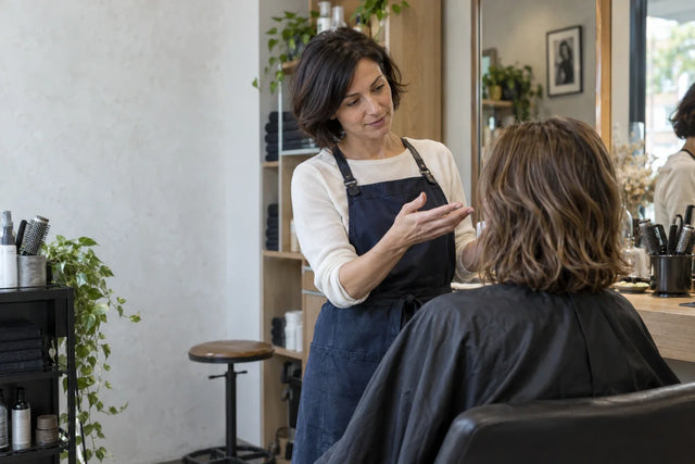 Une coiffeuse échange avec sa cliente avant la coupe.